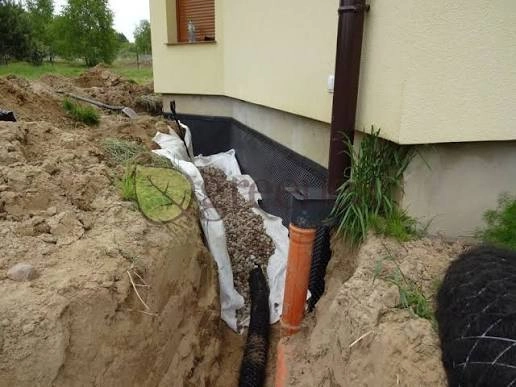 Wykop przy budynku z rurą drenarską i geowłókniną przy izolacji fundamentów – drenaż opaskowy