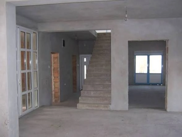 Wnętrze domu w stanie surowym zamkniętym z betonowymi schodami i zamontowanymi oknami