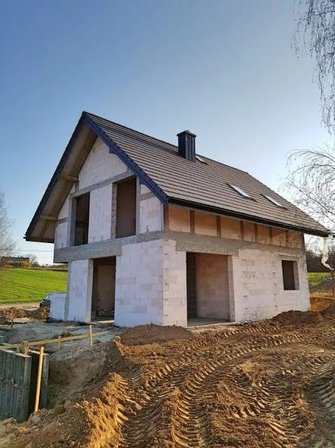 Stan surowy otwarty murowanego domu jednorodzinnego z dachem pokrytym dachówką na terenie budowy