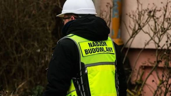Inspektor nadzoru budowlanego w kamizelce i kasku na placu budowy